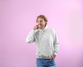 Portrait of man in hoodie sweater on color background. Space for design