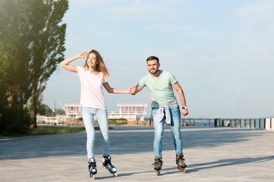Young happy couple roller skating on city street