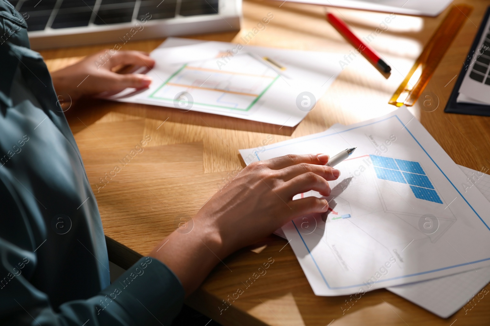 Photo of Woman working on house project with solar panels at table in office, closeup