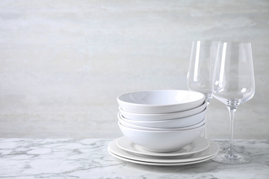 Set of clean dishware on marble table. Space for text