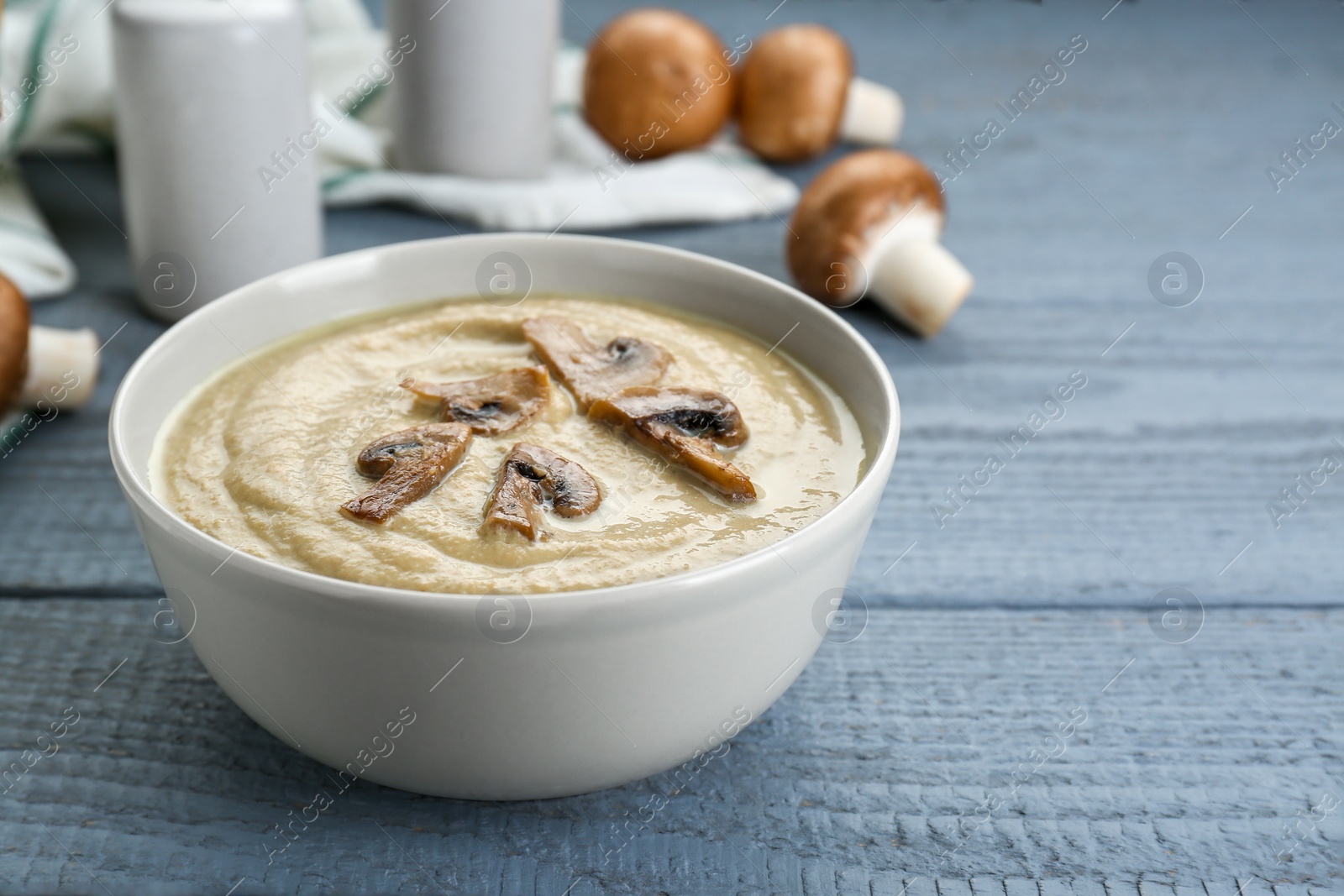 Photo of Delicious mushroom cream soup on light grey wooden table. Space for text