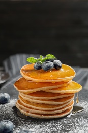 Photo of Tasty pancakes with berries and honey on slate plate