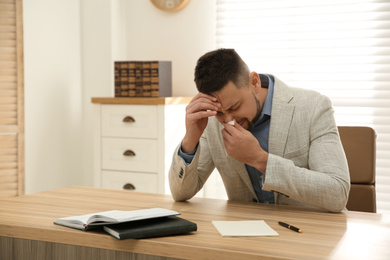 Photo of Sick man sneezing in office. Influenza virus