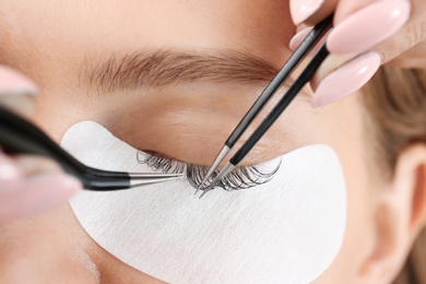 Young woman undergoing eyelash extensions procedure, closeup