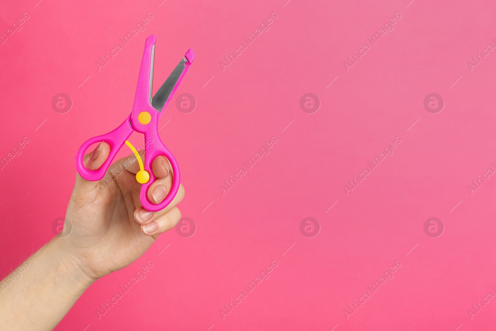 Photo of Woman holding small scissors on pink background, closeup. Space for text