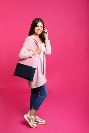 Full length portrait of young woman with textile bag on pink background