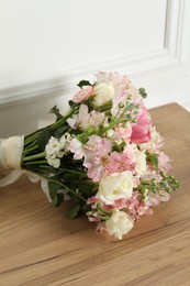 Beautiful bouquet of fresh flowers on wooden table near white wall