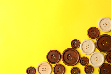 Many colorful sewing buttons on yellow background, flat lay. Space for text