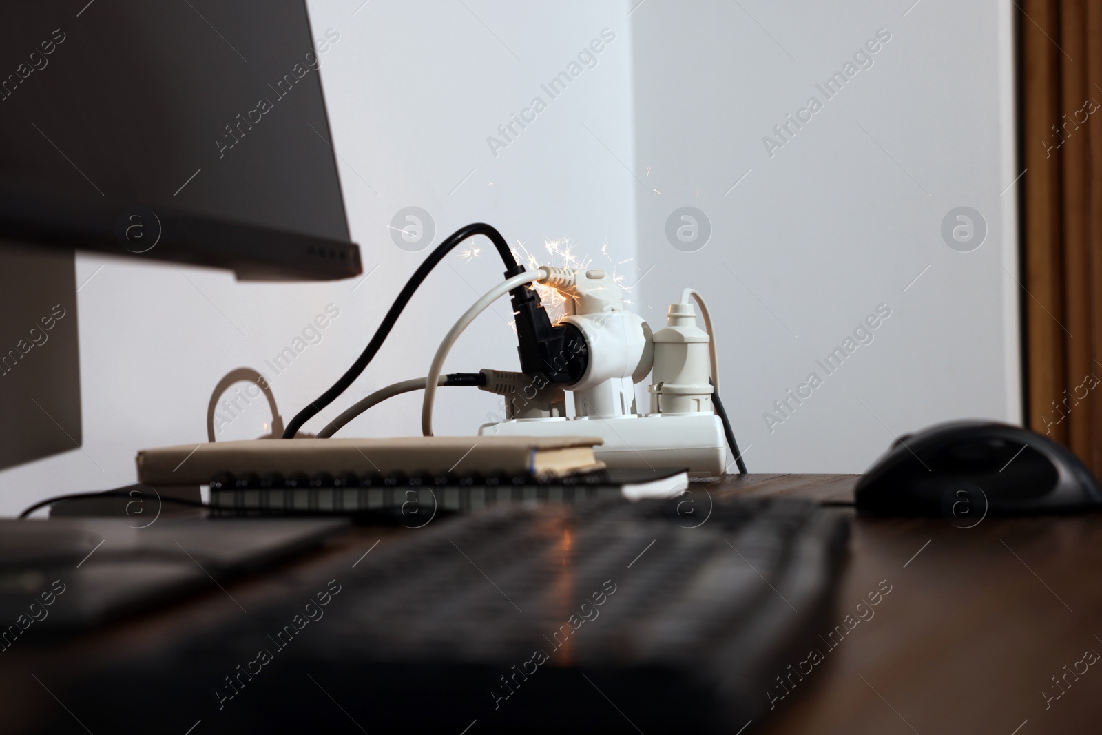 Photo of Inflamed plug in power strip indoors on wooden table. Electrical short circuit