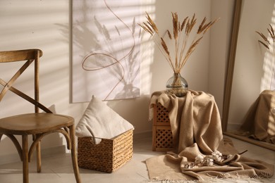 Vase with decorative dried plants and painting in stylish room interior