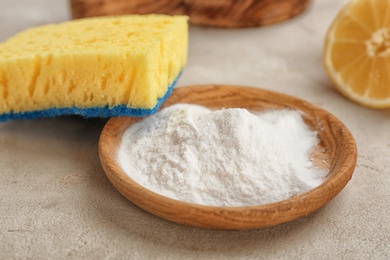 Photo of Bowl with baking soda and sponge on gray table