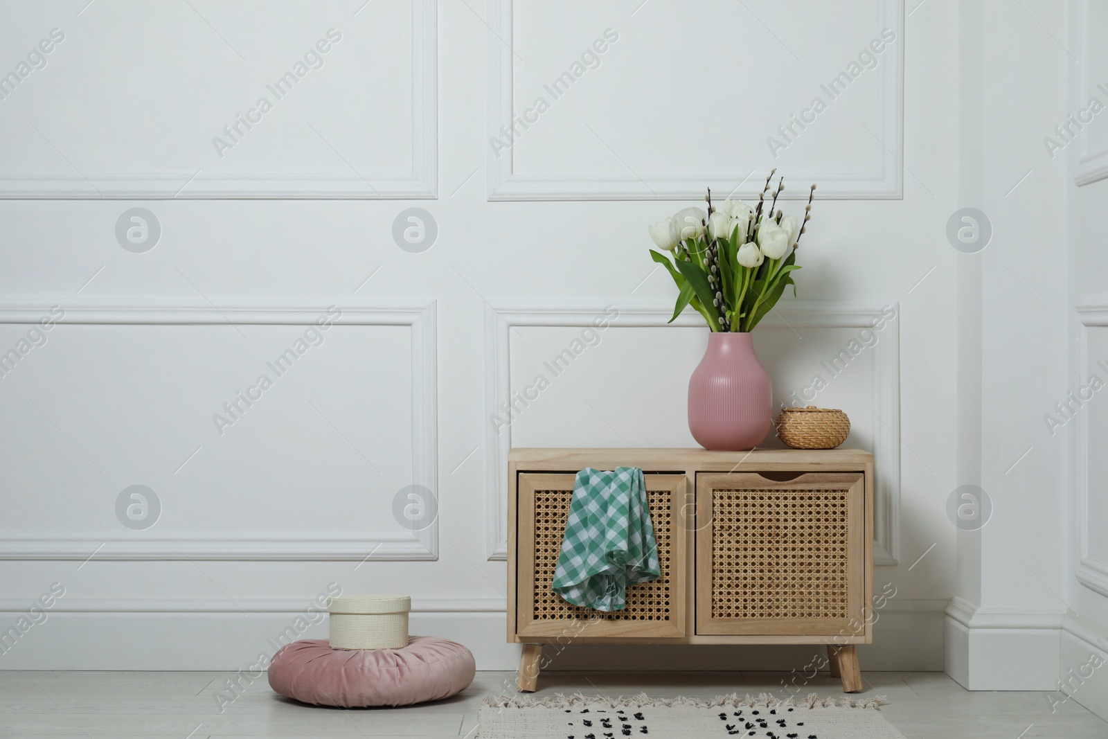 Photo of Beautiful bouquet of willow branches and tulips in vase on commode indoors, space for text