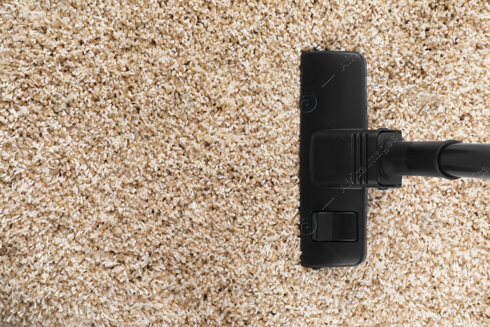 Photo of Hoovering carpet with modern vacuum cleaner indoors, top view. Space for text