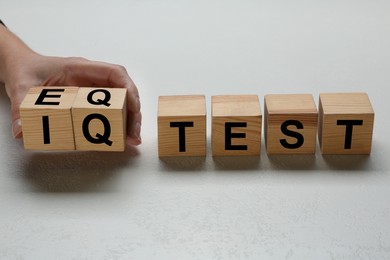 Photo of Woman taking cubes with text IQ Test on light background, closeup