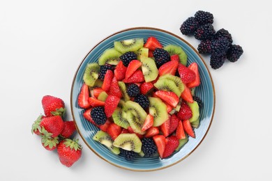 Photo of Plate of yummy fruit salad and ingredients on light blue background, flat lay