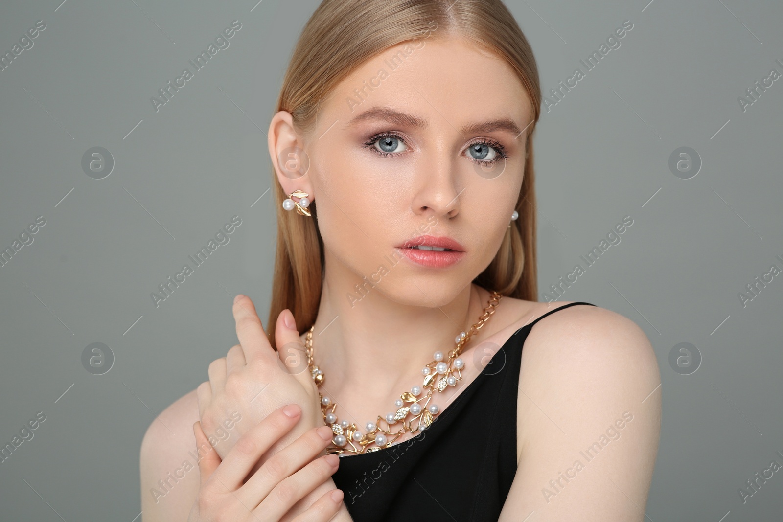 Photo of Beautiful young woman with elegant jewelry on gray background