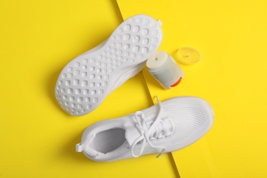 Photo of Stylish footwear and shoe care accessory on yellow background, flat lay