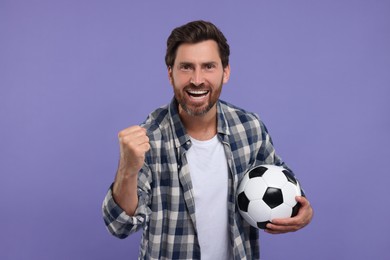 Photo of Emotional sports fan with soccer ball on purple background