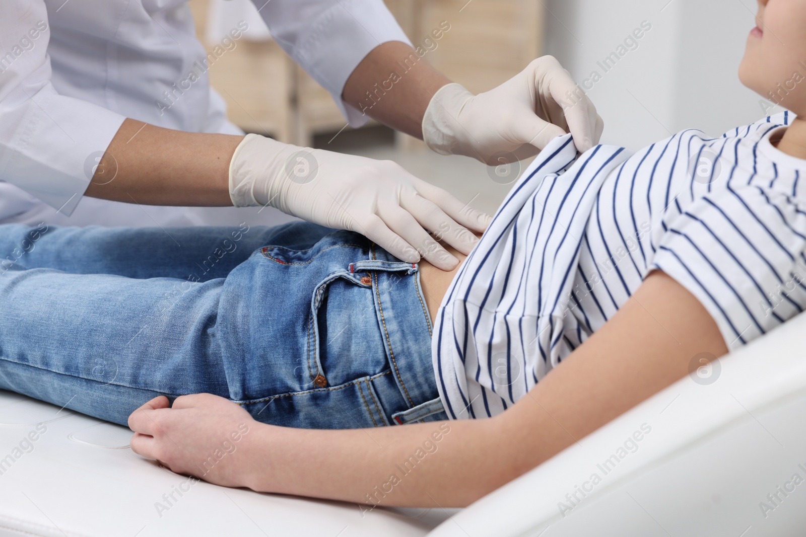 Photo of Gastroenterologist examining girl with stomach ache on couch in clinic, closeup