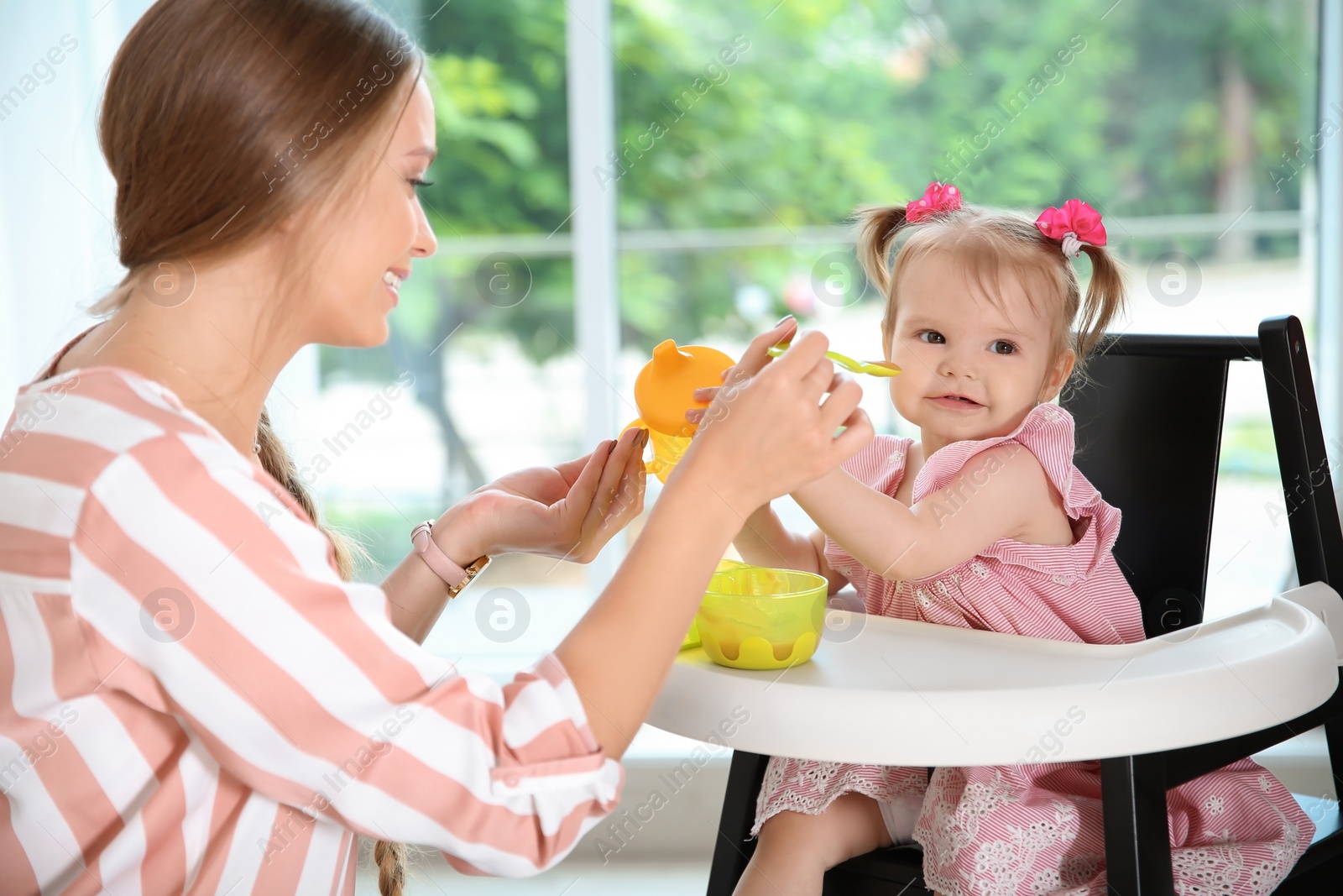 Photo of Caring mother feeding her cute little baby with healthy food at home