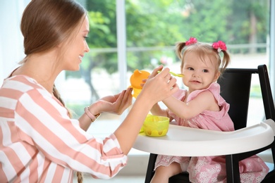 Caring mother feeding her cute little baby with healthy food at home