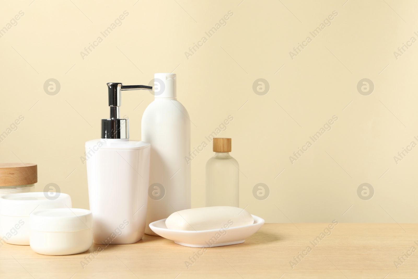 Photo of Different bath accessories on wooden table against beige background. Space for text