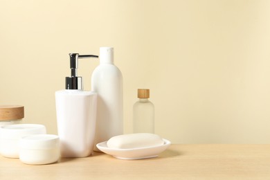 Different bath accessories on wooden table against beige background. Space for text