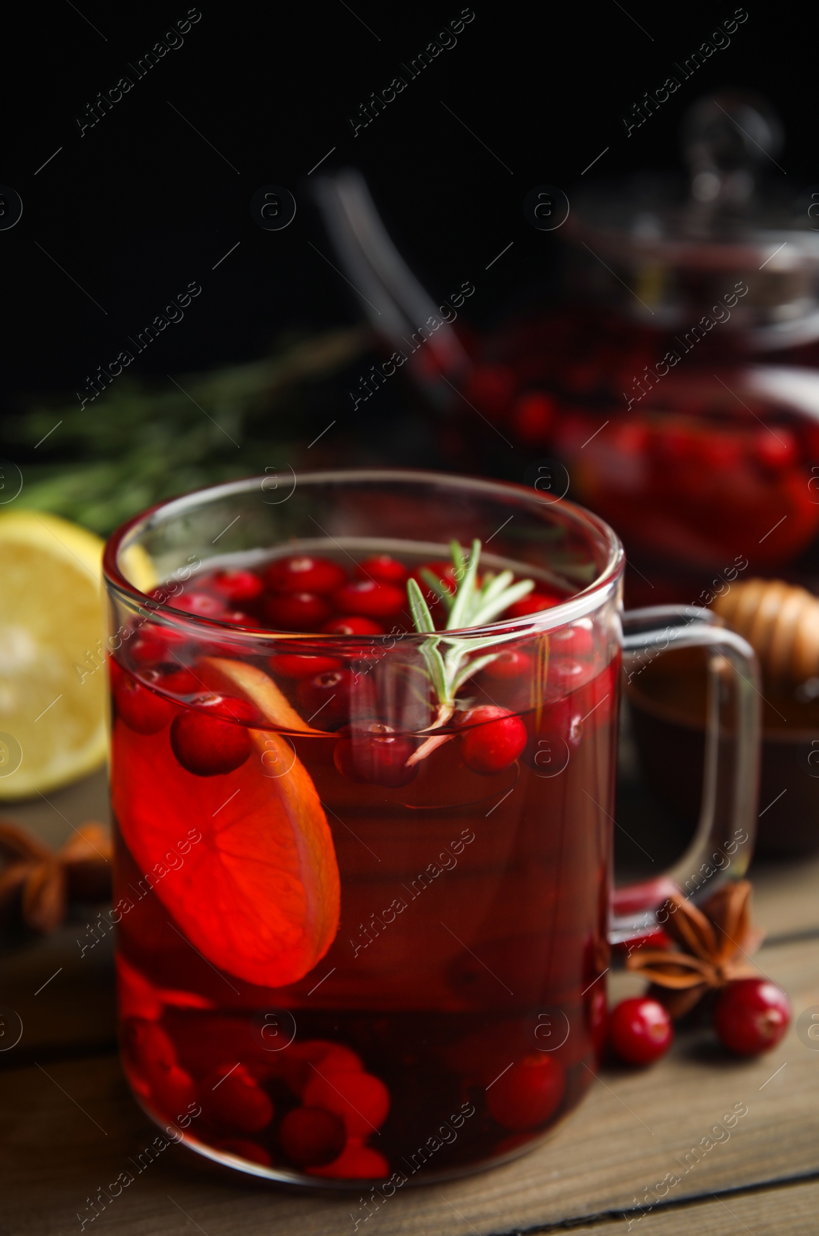 Photo of Tasty hot cranberry tea with rosemary and lemon on wooden table