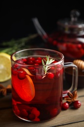 Photo of Tasty hot cranberry tea with rosemary and lemon on wooden table
