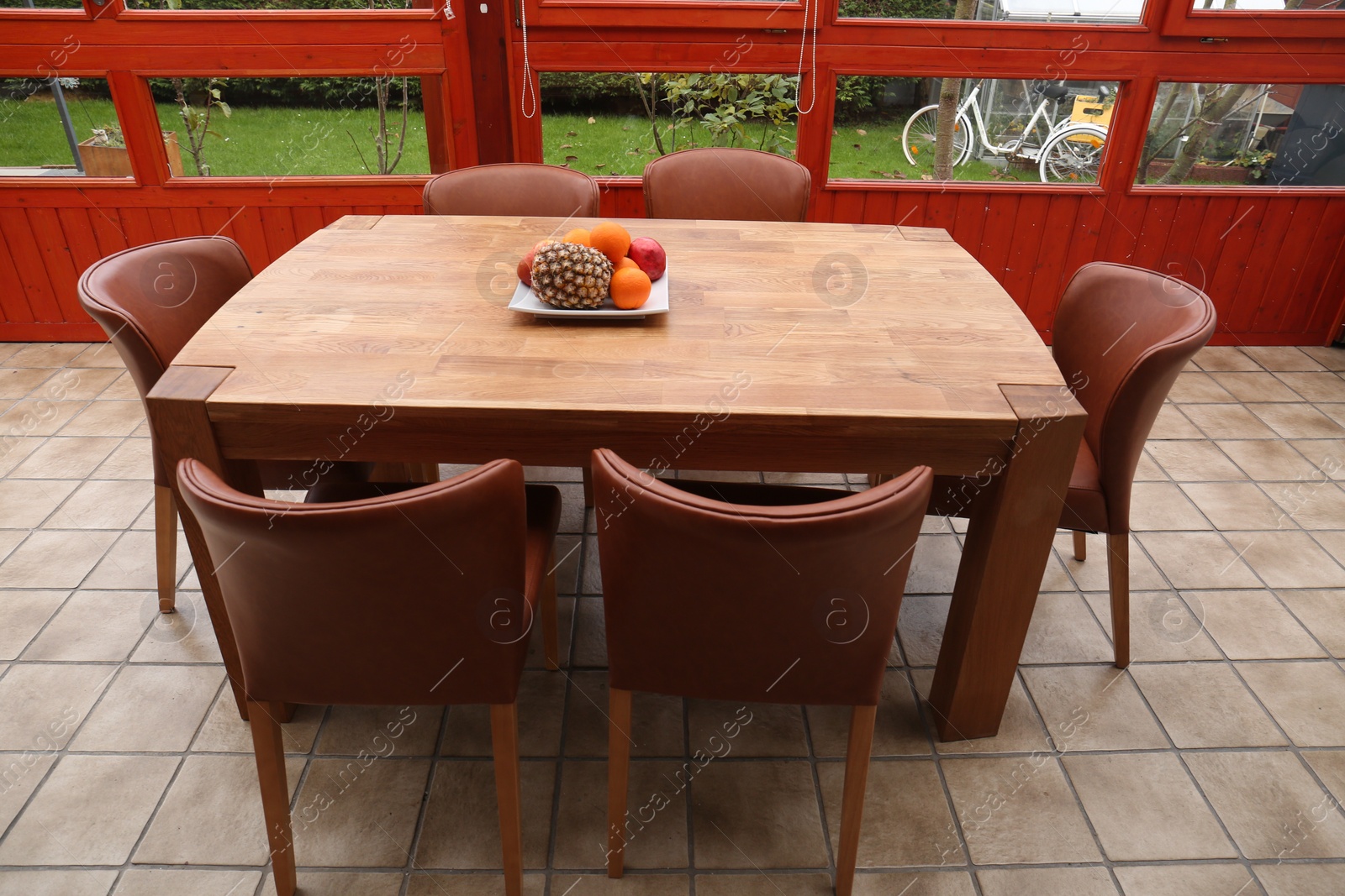 Photo of Wooden table with fruits and stylish chairs on terrace