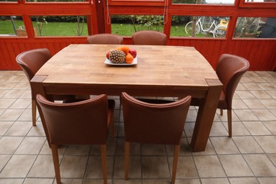 Wooden table with fruits and stylish chairs on terrace