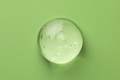 Photo of Sample of clear cosmetic gel on light green background, top view