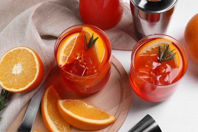 Aperol spritz cocktail, rosemary and orange slices in glasses on white wooden table, above view