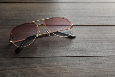 Photo of New stylish sunglasses on wooden table, space for text