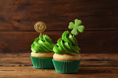 Photo of Delicious decorated cupcakes on wooden table. St. Patrick's Day celebration