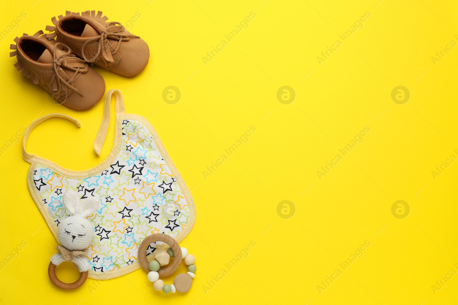 Photo of Flat lay composition with drool baby bib and accessories on yellow background. Space for text