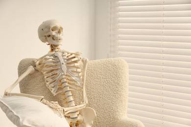 Photo of Waiting concept. Human skeleton sitting in armchair indoors, space for text