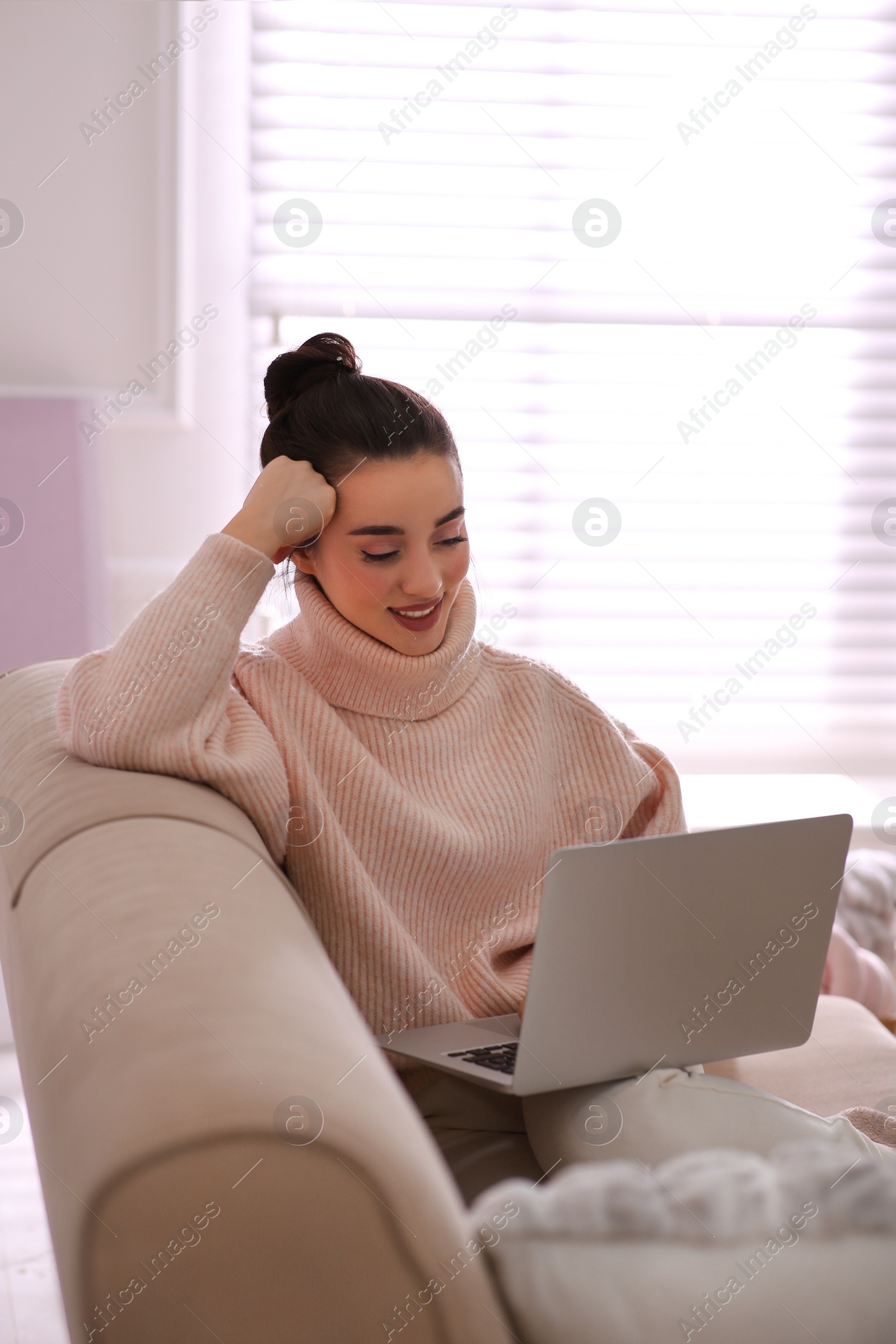 Photo of Beautiful young woman with laptop relaxing at home. Cozy atmosphere