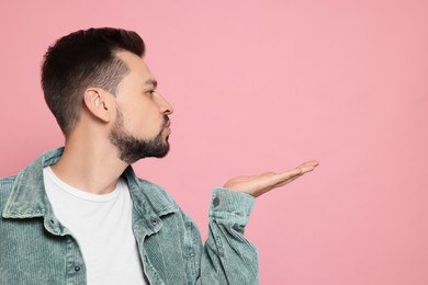 Photo of Handsome man blowing kiss on pink background. Space for text