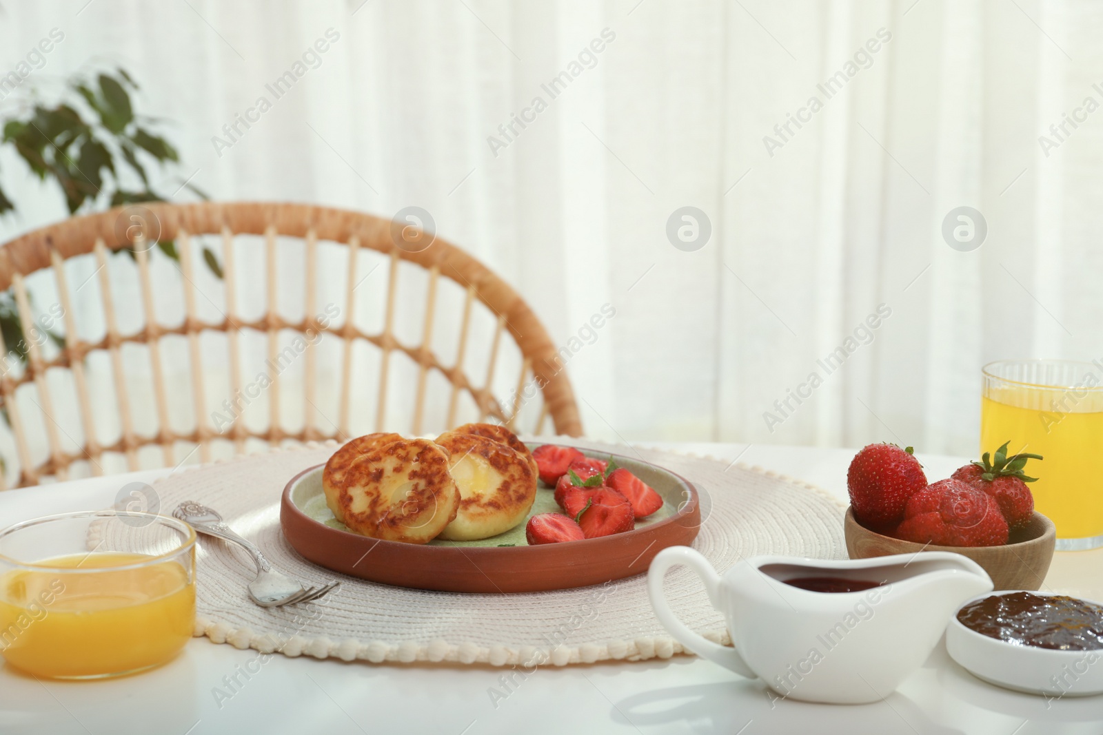 Photo of Delicious cottage cheese pancakes with fresh strawberries served on white table indoors