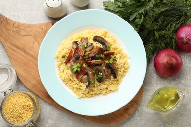 Tasty millet porridge with mushrooms, bacon and green onion on grey textured table, flat lay