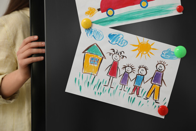 Photo of Woman opening refrigerator's door with drawings, closeup