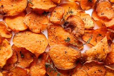 Sweet potato chips with herbs on white background, top view