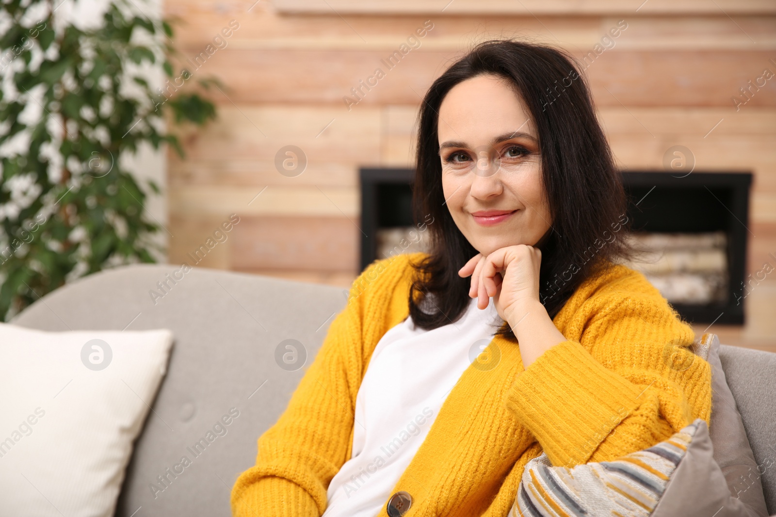 Photo of Beautiful mature woman on sofa at home. Space for text