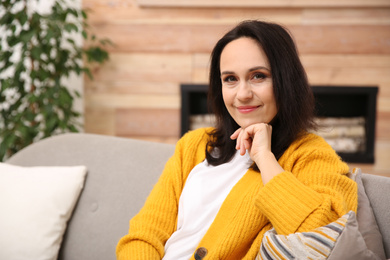 Photo of Beautiful mature woman on sofa at home. Space for text