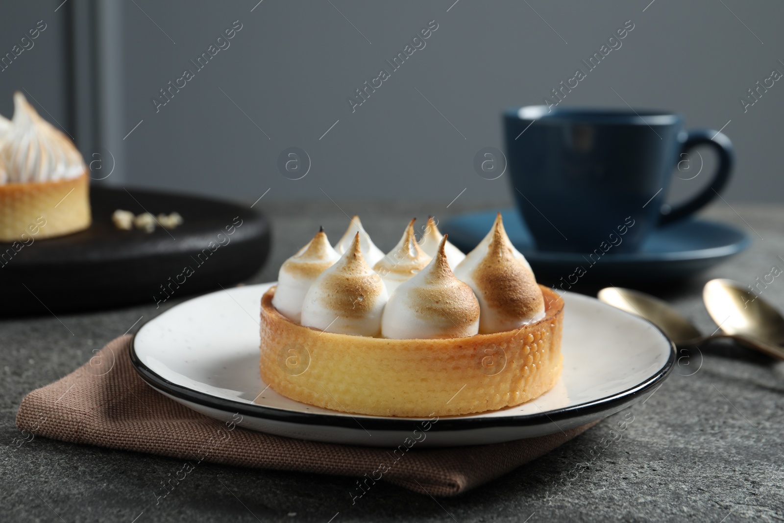 Photo of Tartlet with meringue served on dark grey table, closeup. Tasty dessert