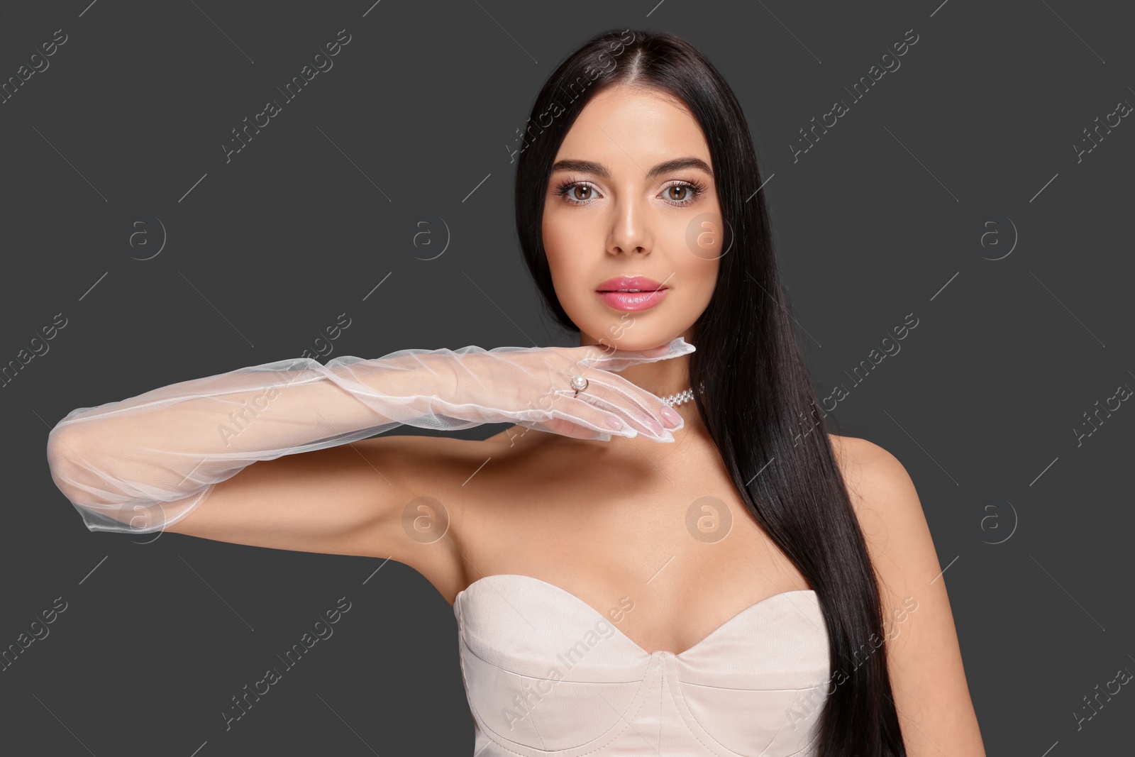 Photo of Portrait of beautiful young woman in evening gloves on black background