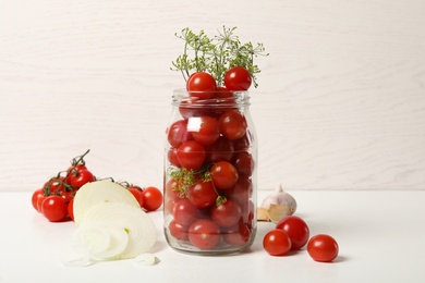 Pickling jar with fresh tomatoes on white table