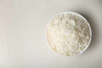 Photo of Bowl of boiled rice on light background, top view with space for text