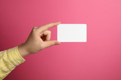 Photo of Woman holding blank gift card on pink background, closeup